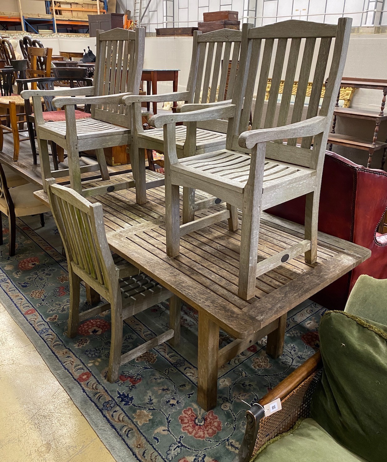 A rectangular weathered teak garden table, length 183cm, depth 92cm, height 73cm and seven Lister teak garden elbow chairs